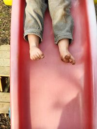 Low section of child playing on red slide