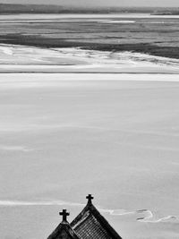 Cross on roof of mont saint-michel against snow covered landscape