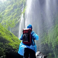 Rear view of man looking at waterfall