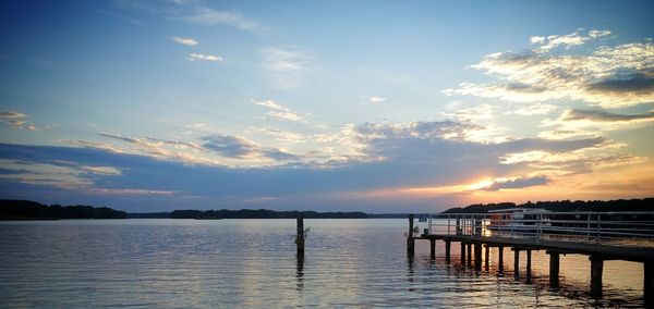 Pier over lake against sky during sunset