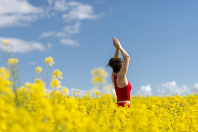 Woman performing yoga while standing in oilseed rape field