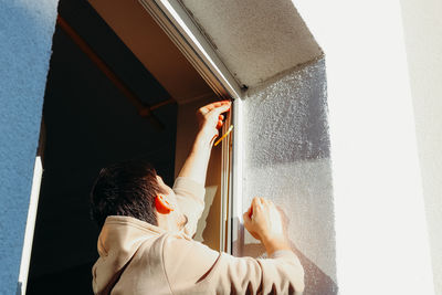 Side view of woman standing against wall
