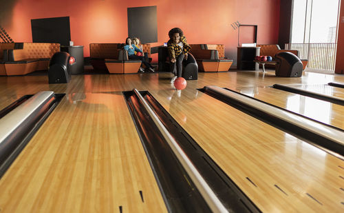 Young man playing throwing ball at bowling alley