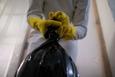 Low section of person holding garbage bag