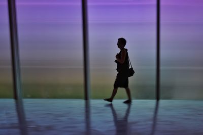 Full length of woman walking on floor by glass window