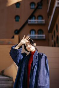 Young woman looking away while standing against building