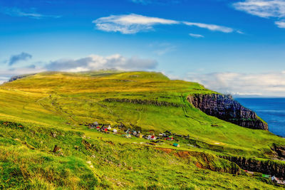 Scenic view of green landscape and sea against sky