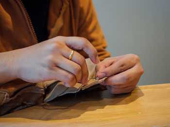 Midsection of woman sewing fabric on table