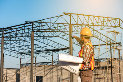 Man working at construction site against sky