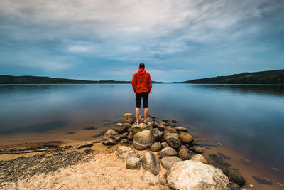 Rear view of man standing on beach against sky