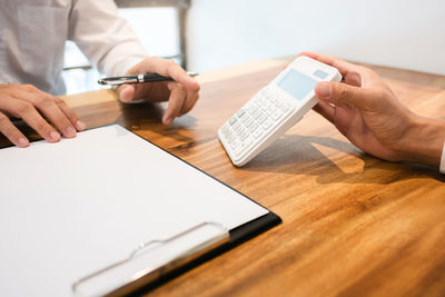 Midsection of man using mobile phone on table