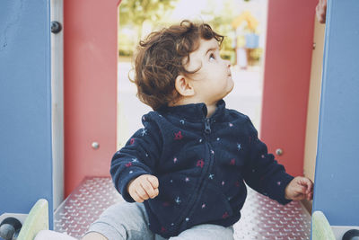 Cute boy looking away while sitting outdoors