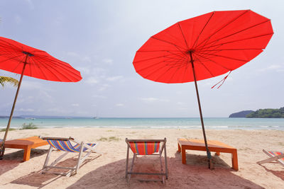 Umbrellas and chairs on beach against sky