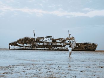 Abandoned ship in sea against sky during winter