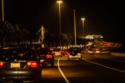 Cars on road against illuminated city at night