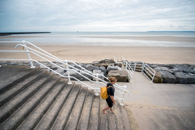 High angle view of woman moving down on steps against beach