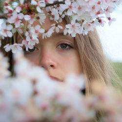 Close-up portrait of woman looking through flowers