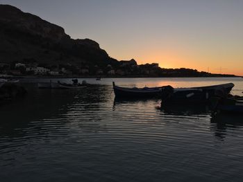 Boats moored in sea at sunset