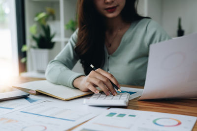 Midsection of woman using laptop on table