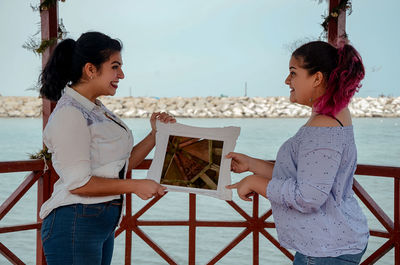 Friends holding mirror frame at gazebo