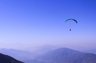 Silhouette person paragliding against sky over mountains