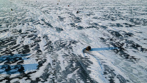 Aerial of frozen lake with patterns and fishing huts in the early morning