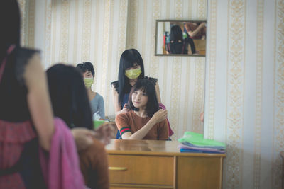 Cropped hands of beautician styling young woman hair in salon