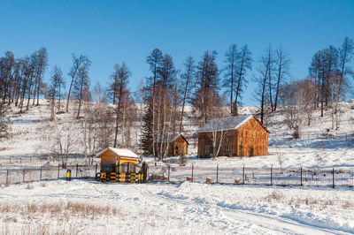 Houses on snow covered field against sky