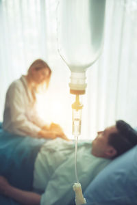 Young woman examining patient lying on bed at hospital