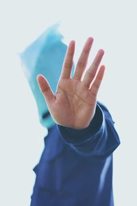 Man gesturing while wearing plastic bag over face against sky