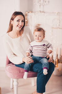 Portrait of smiling woman with daughter sitting at home
