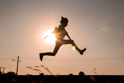 Side view of silhouette woman jumping against sky during sunset