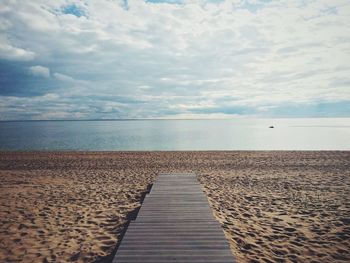 Boardwalk on beach against sky