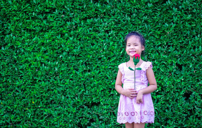 Portrait of a smiling girl standing against green plants