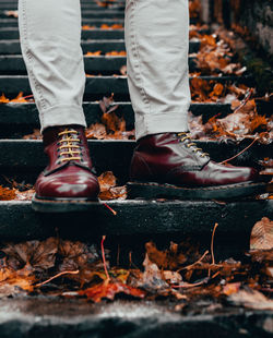 Low section of man standing on autumn leaves