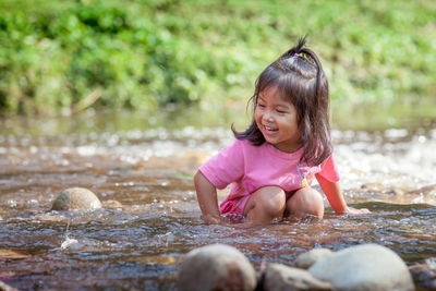 Cheerful girl playing in stream