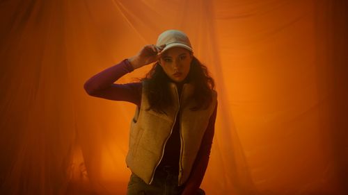Portrait of young woman standing against orange sky
