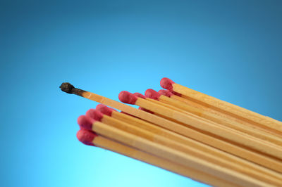 Low angle view of pencils against blue sky