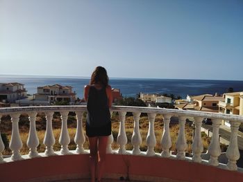 Rear view of woman looking at sea while standing by railing