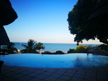 Swimming pool by sea against clear blue sky