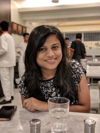 Portrait of a smiling young woman at restaurant table