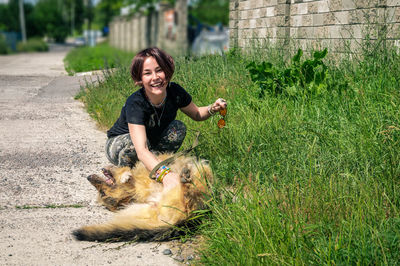 Portrait of young woman with dog on field