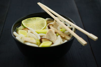 Japanese food soup with udon noodles, chicken, mushrooms leeks and lime concept of asian food