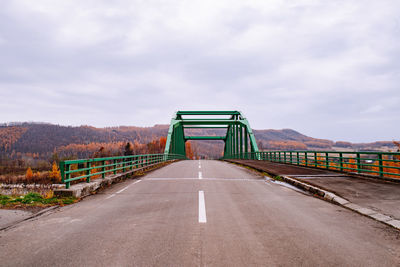 Road leading towards bridge against sky