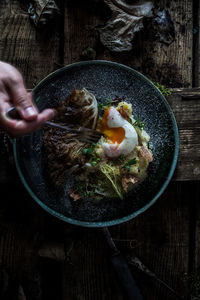 Cropped hand of person picking food from plate