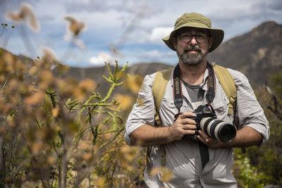 Portrait of man photographing against plants