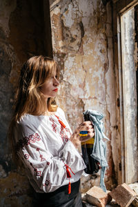 Portrait of young woman standing against old building