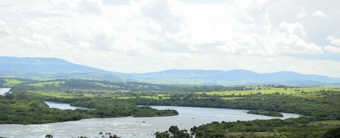 Scenic view of river by mountains against sky