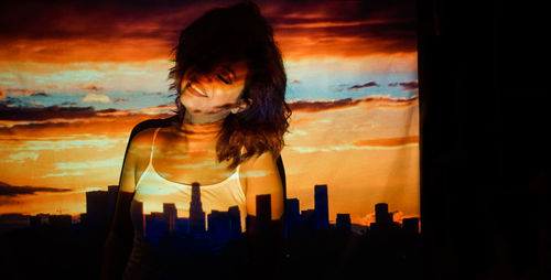 Portrait of woman against cityscape during sunset