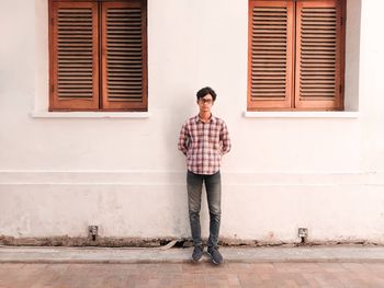 Full length of young man standing against building